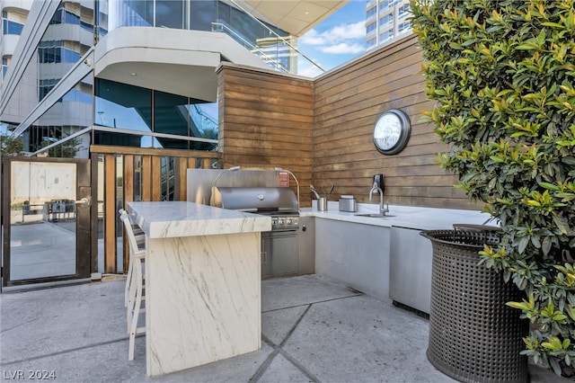 view of patio featuring area for grilling, sink, and a balcony