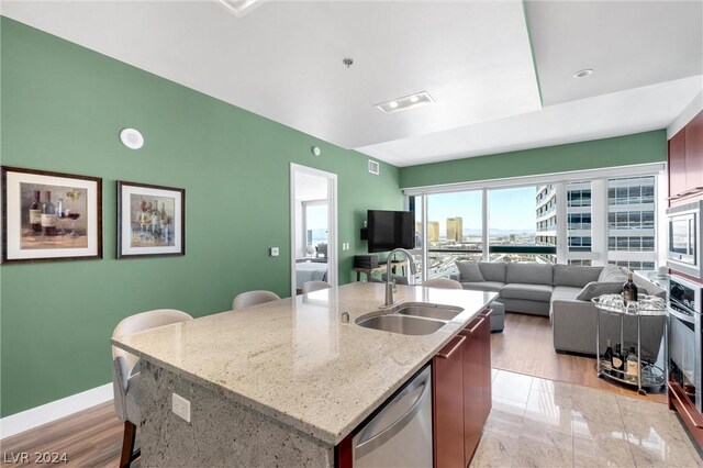 kitchen featuring sink, a center island with sink, light wood-type flooring, and appliances with stainless steel finishes