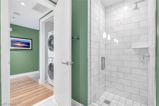 bathroom featuring tile flooring, walk in shower, and stacked washer and dryer