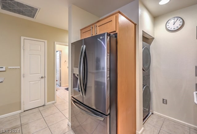 kitchen featuring light tile flooring, stainless steel refrigerator with ice dispenser, and stacked washer and dryer