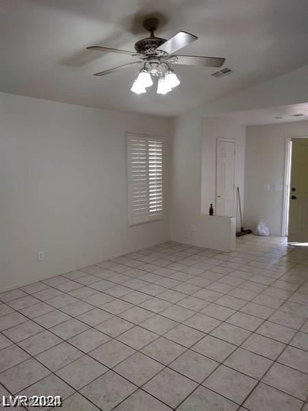 tiled spare room featuring vaulted ceiling and ceiling fan