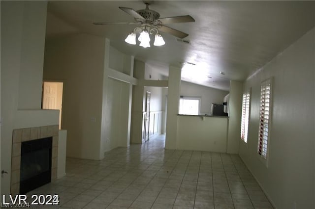 unfurnished living room featuring ceiling fan, lofted ceiling, a fireplace, and light tile patterned floors