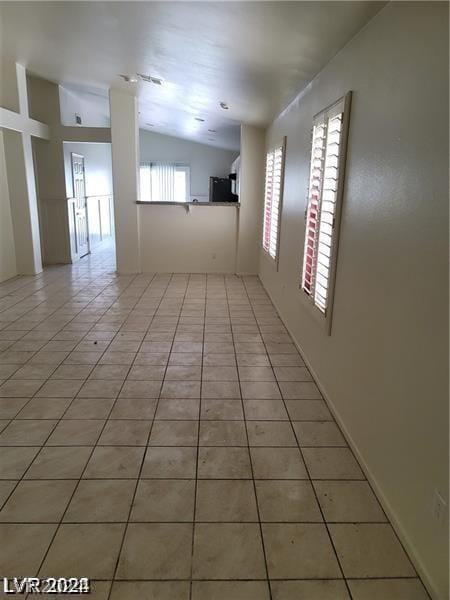 tiled spare room featuring lofted ceiling