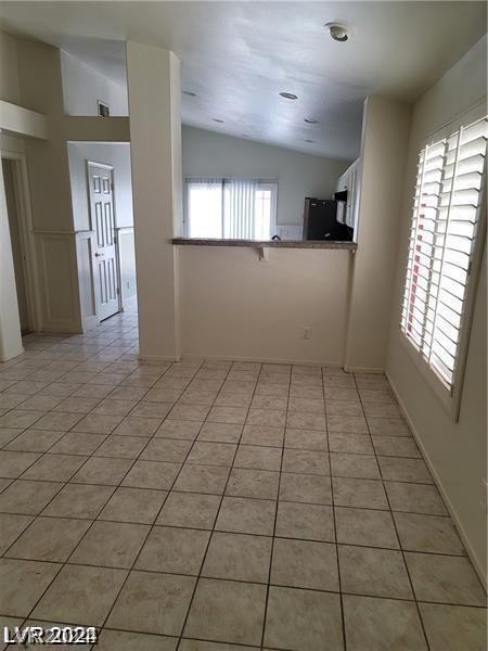 spare room featuring light tile patterned flooring and vaulted ceiling