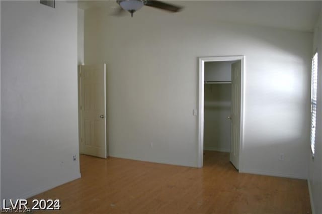 unfurnished bedroom with a walk in closet, a closet, light hardwood / wood-style flooring, and ceiling fan