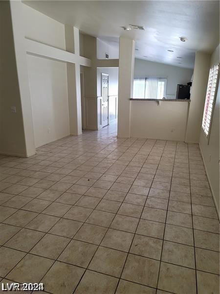 empty room with light tile patterned floors and vaulted ceiling