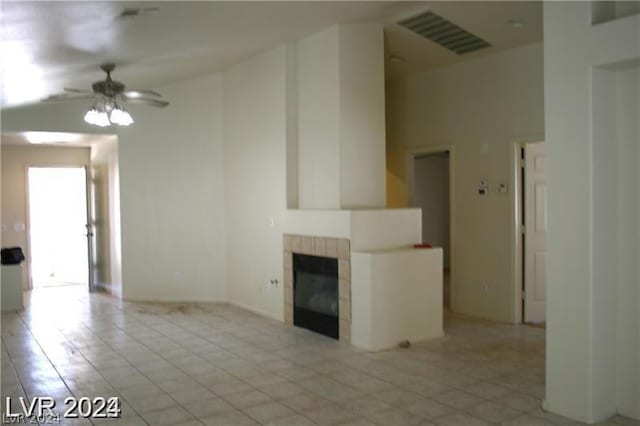 unfurnished living room with a tile fireplace and ceiling fan