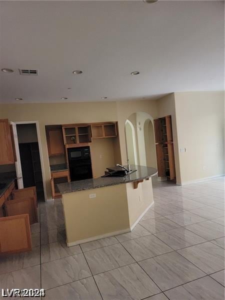 kitchen featuring dark stone counters, a breakfast bar, and black microwave