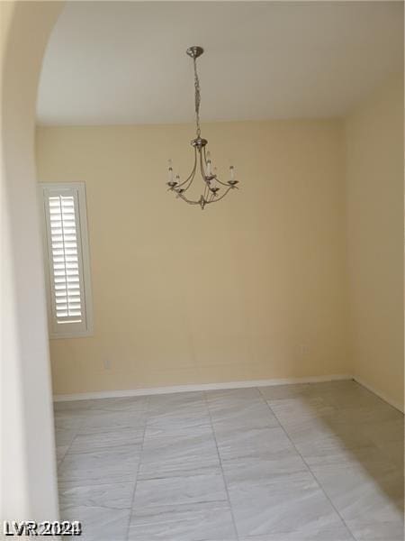 spare room with a notable chandelier