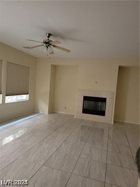 unfurnished living room with ceiling fan and a tiled fireplace