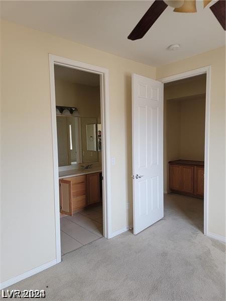 unfurnished bedroom with ceiling fan, ensuite bath, and light carpet