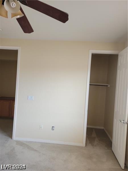 unfurnished bedroom featuring a spacious closet, light colored carpet, ceiling fan, and a closet