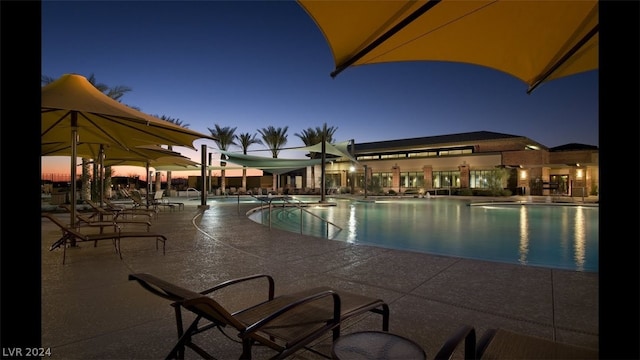 pool at dusk with a patio area