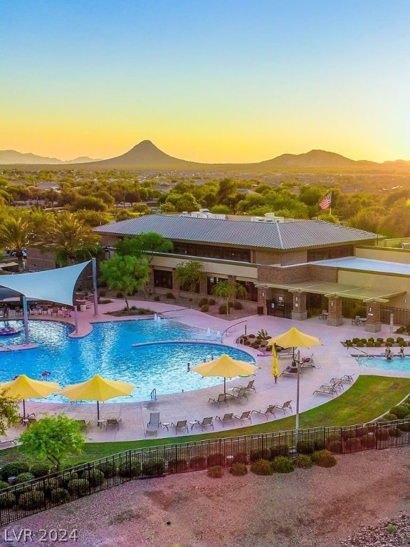 pool at dusk with a mountain view and a patio area