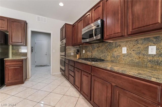 kitchen featuring stone counters, appliances with stainless steel finishes, light tile patterned floors, and decorative backsplash