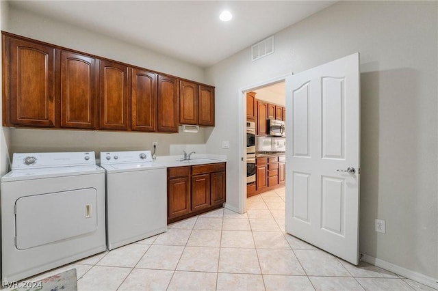 washroom with cabinets, washing machine and dryer, sink, and light tile patterned floors