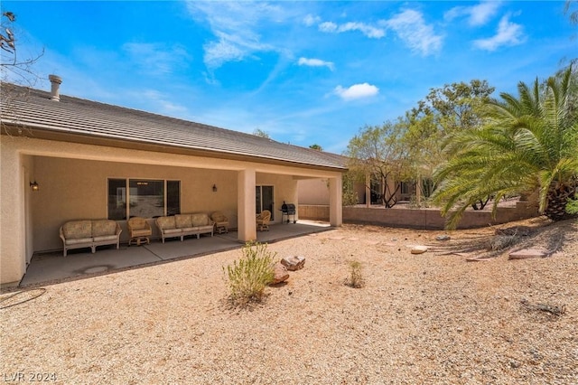 rear view of property featuring an outdoor living space and a patio area