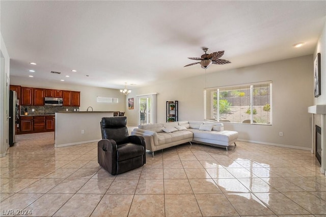 living room featuring light tile patterned flooring, ceiling fan with notable chandelier, and a wealth of natural light