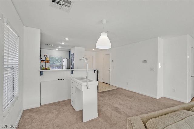 kitchen with stainless steel fridge, white cabinetry, hanging light fixtures, and light carpet