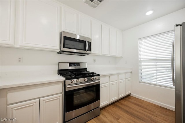 1161 Gecko Rd, Henderson, NV 89002 - kitchen with stainless steel appliances, baseboards, white cabinetry, and light wood-style flooring