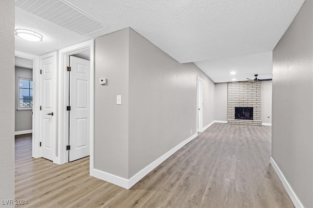 hallway featuring light hardwood / wood-style floors and a textured ceiling