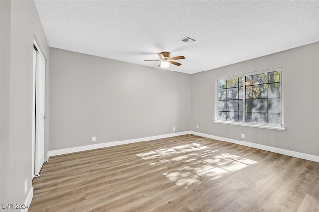 spare room with hardwood / wood-style floors, ceiling fan, and a textured ceiling