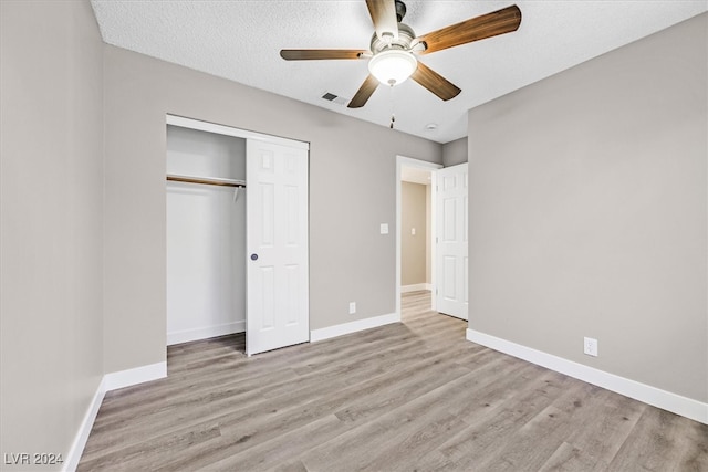 unfurnished bedroom with a closet, a textured ceiling, light hardwood / wood-style floors, and ceiling fan