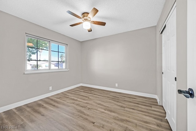 unfurnished bedroom with a textured ceiling, a closet, hardwood / wood-style flooring, and ceiling fan