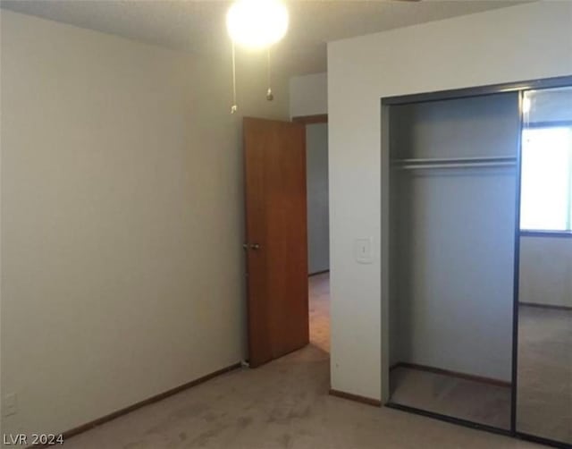 unfurnished bedroom with light colored carpet and a closet