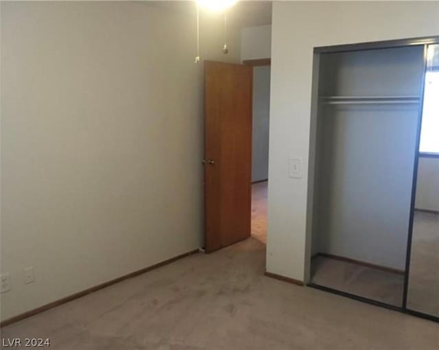 unfurnished bedroom featuring light colored carpet and a closet