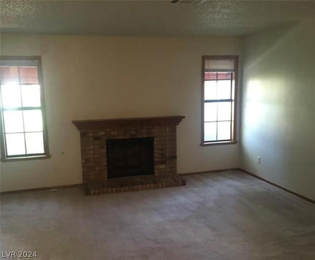 unfurnished living room with carpet flooring, a textured ceiling, and a fireplace