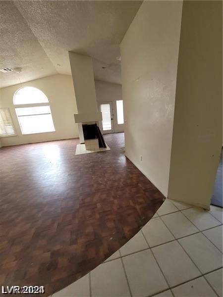 unfurnished living room featuring a textured ceiling and vaulted ceiling