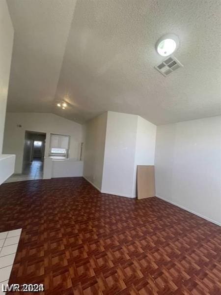 bonus room with lofted ceiling, a textured ceiling, and parquet floors