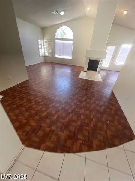 unfurnished living room featuring tile patterned flooring and lofted ceiling