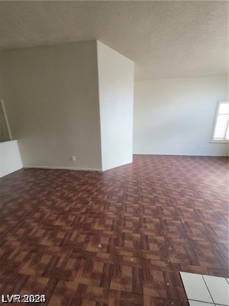 spare room with dark parquet flooring and a textured ceiling