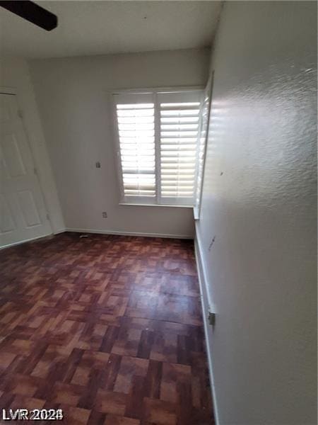 empty room featuring ceiling fan and dark parquet floors