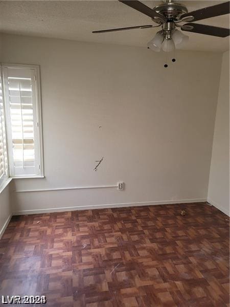 unfurnished room with dark parquet flooring and ceiling fan