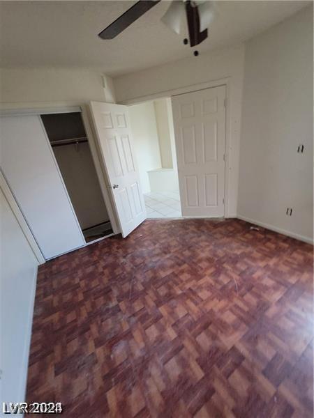 unfurnished bedroom featuring parquet floors, a closet, and ceiling fan