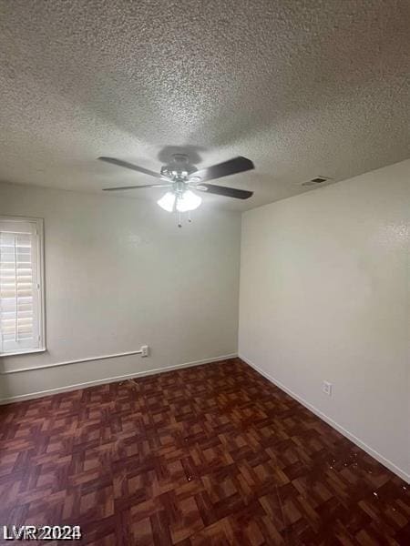 unfurnished room with dark parquet flooring, ceiling fan, and a textured ceiling