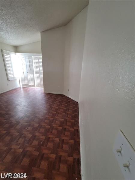 empty room featuring a textured ceiling and dark parquet floors