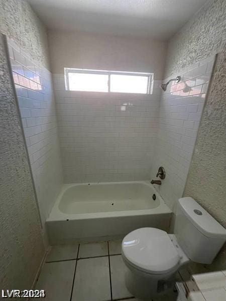 bathroom with tile patterned floors, tiled shower / bath combo, and toilet