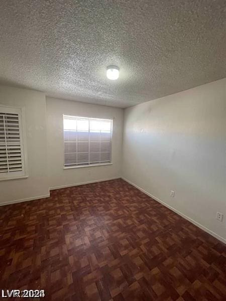 unfurnished room with dark parquet floors and a textured ceiling