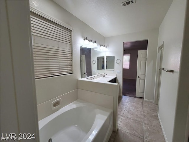 bathroom with tile patterned floors, a washtub, and vanity