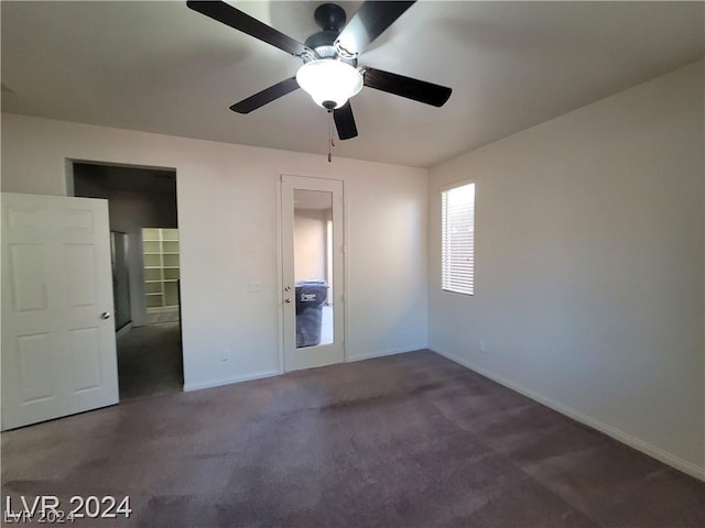 unfurnished bedroom featuring ceiling fan and dark carpet