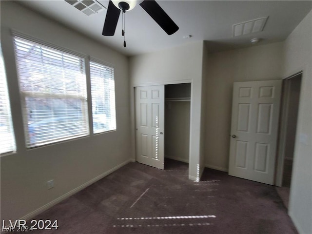 unfurnished bedroom with a closet, dark carpet, and ceiling fan