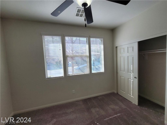 unfurnished bedroom with dark colored carpet, ceiling fan, and a closet