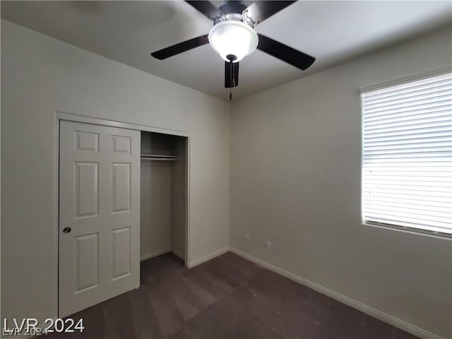 unfurnished bedroom with dark colored carpet, ceiling fan, and a closet