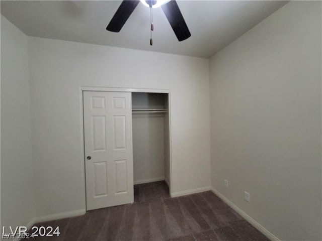 unfurnished bedroom featuring dark colored carpet, a closet, and ceiling fan