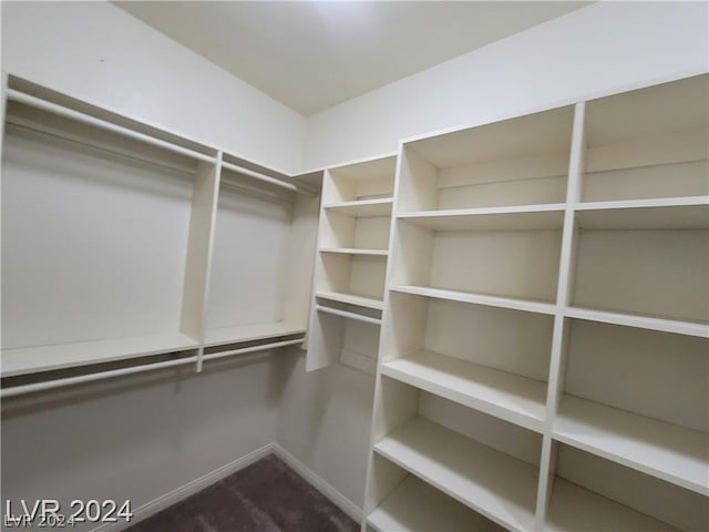 walk in closet featuring dark carpet