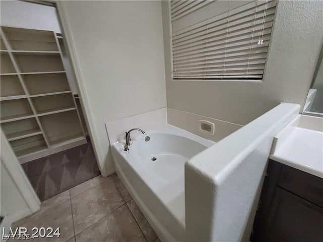 bathroom with tile patterned floors, a tub, and vanity